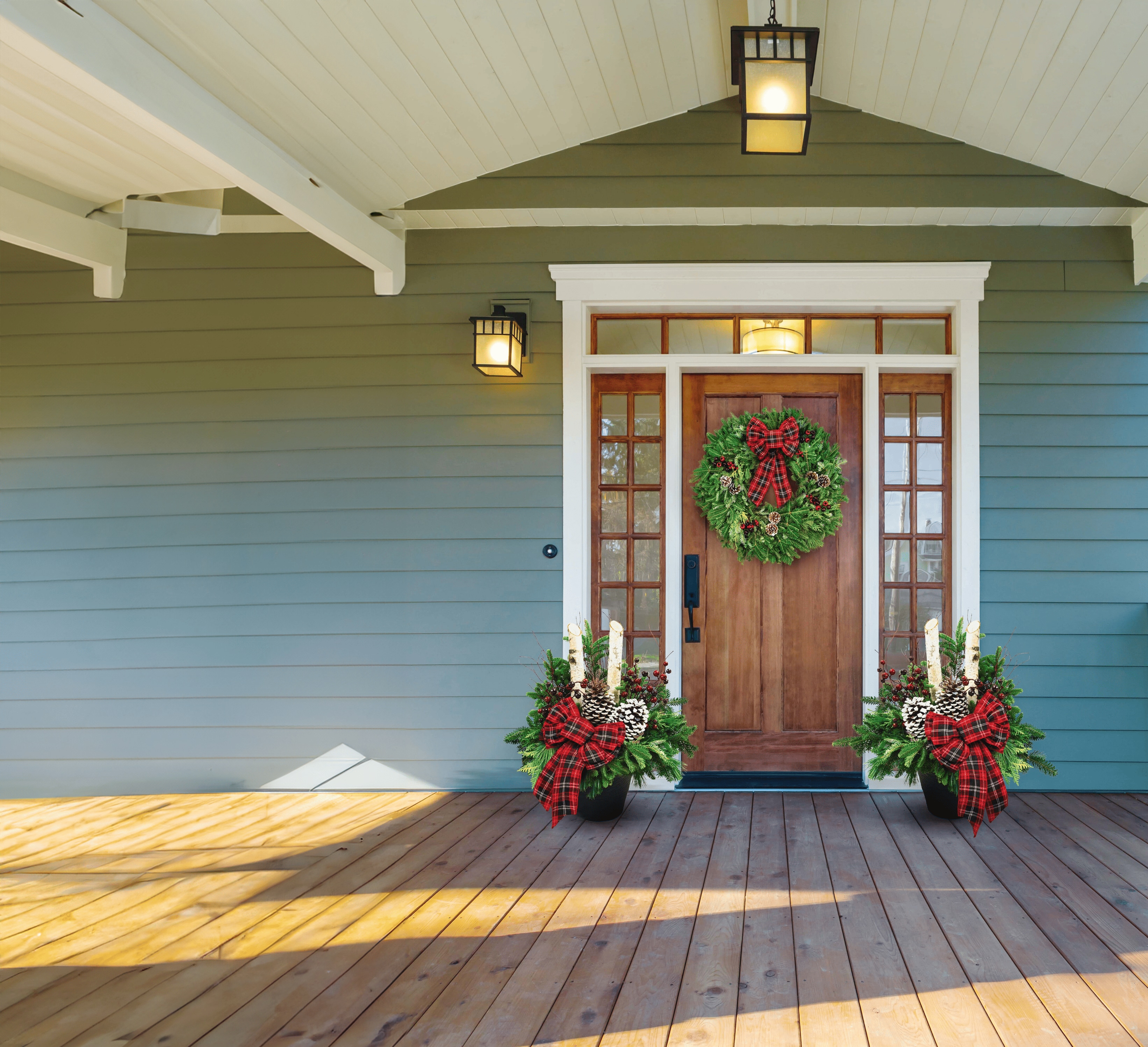 Image of a the front door of a house that has been decorated for christmas with a wreath and some planters by either side of the door