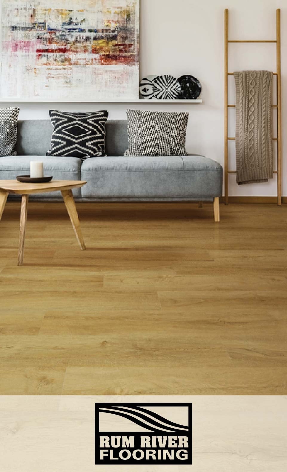 A minimalist living room with a grey sofa, wooden coffee table, and a Rum River Flooring logo