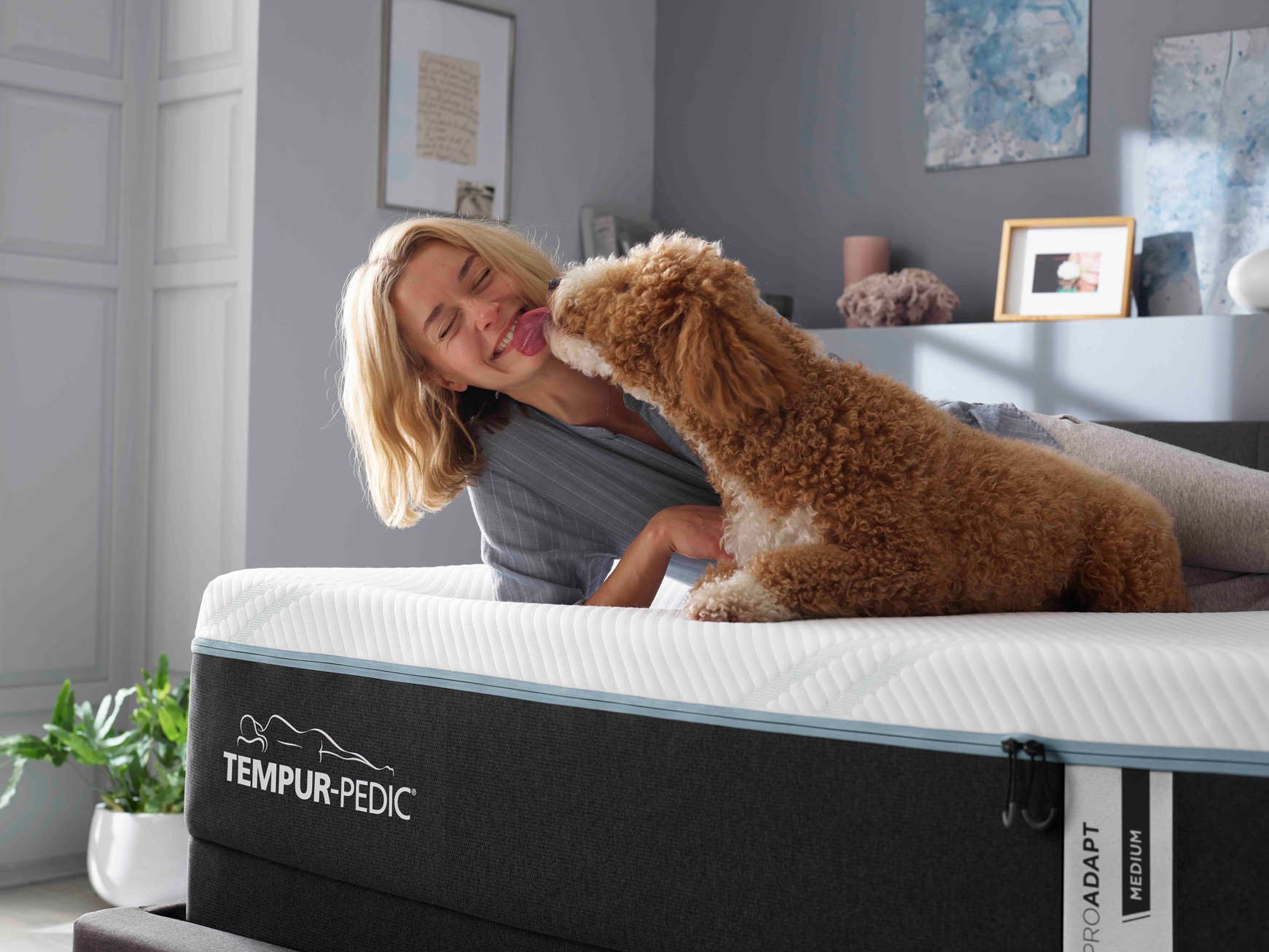 Woman and brown dog on a Tempur-Pedic mattress in a bedroom