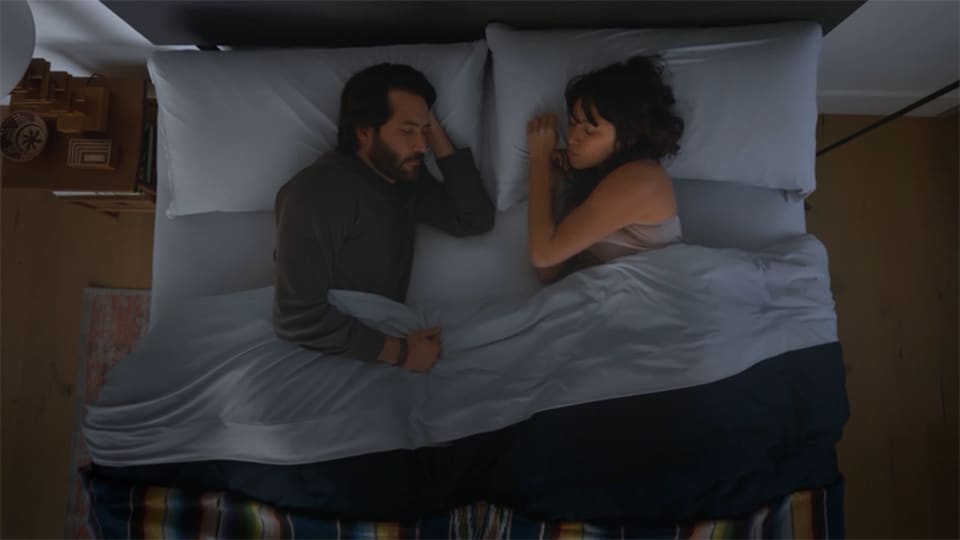 Top view of a couple talking on a bed, in a dimly lit room