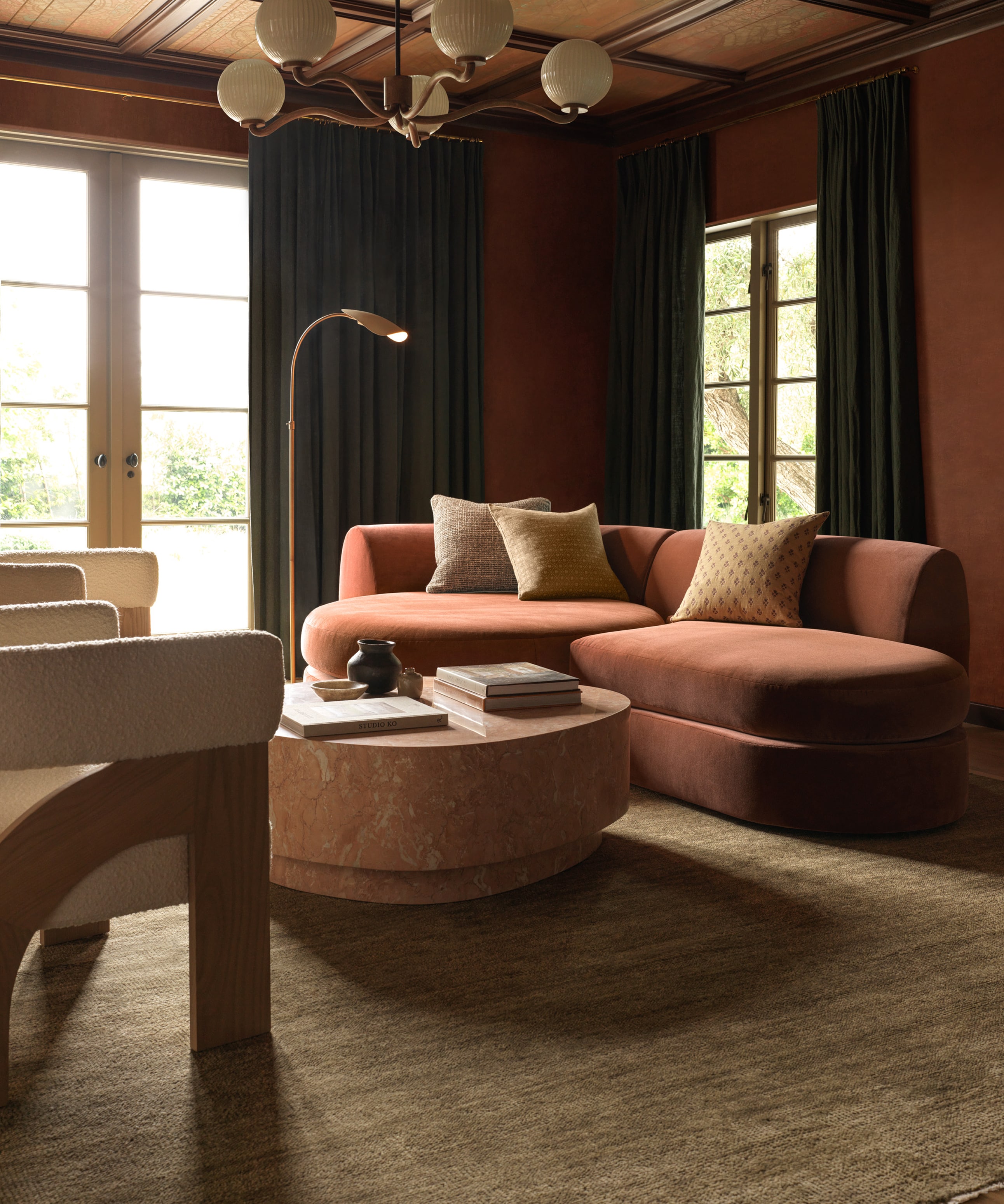 Elegant living room with plush pink sofas, wooden tables, ambient lighting, and large windows
