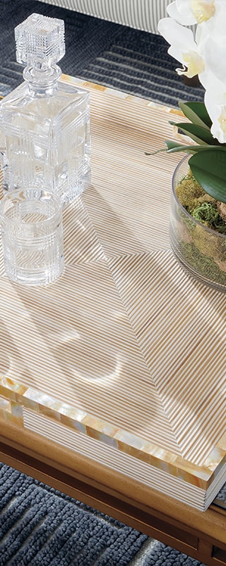 Crystal decanter and glass on a striped tray with a plant beside, on a textured rug