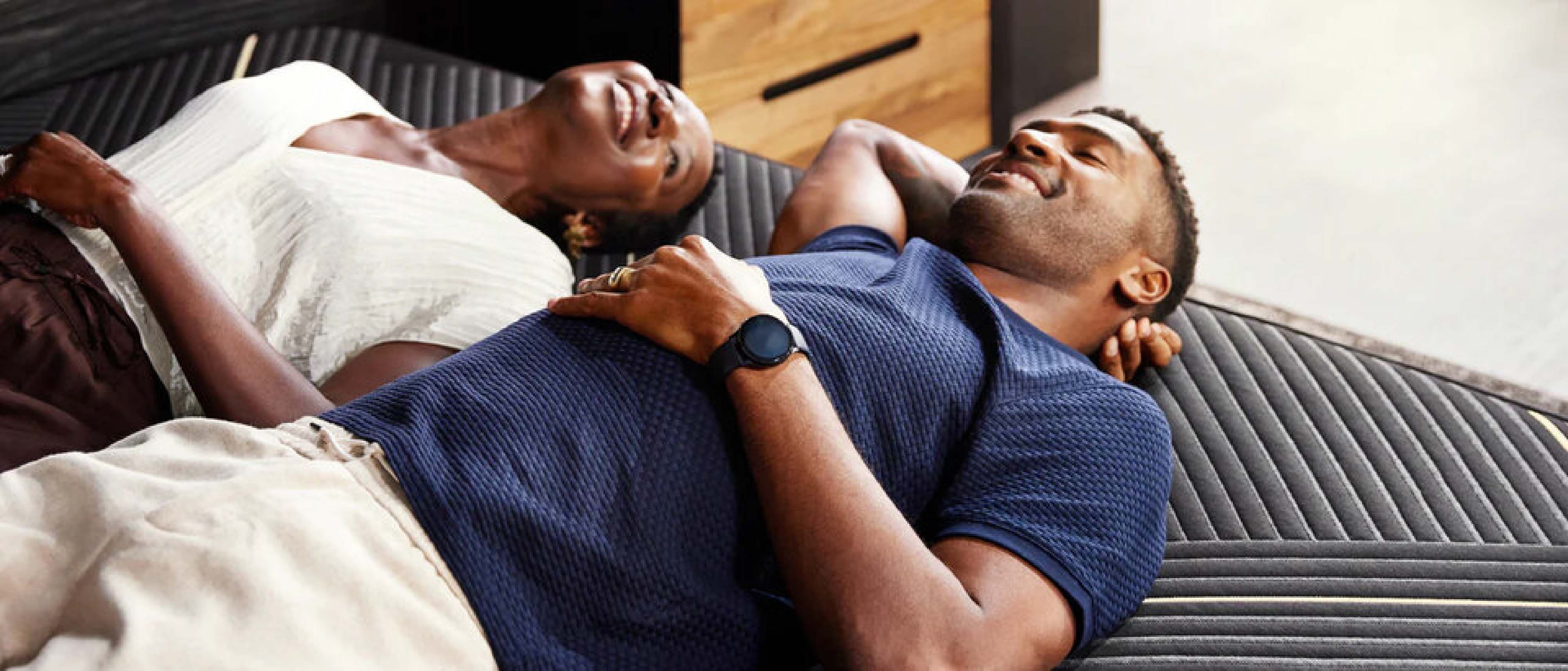 Two men resting on a couch, one lying down and the other sitting beside him