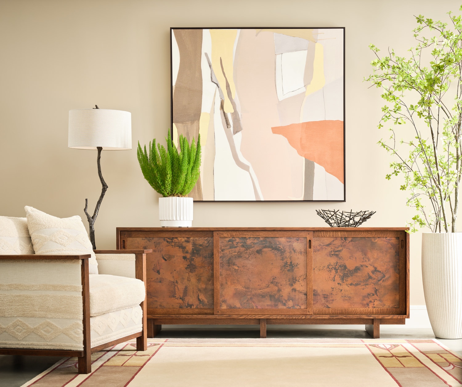 Modern living room with abstract art above a wooden sideboard, white armchair, and decorative plants