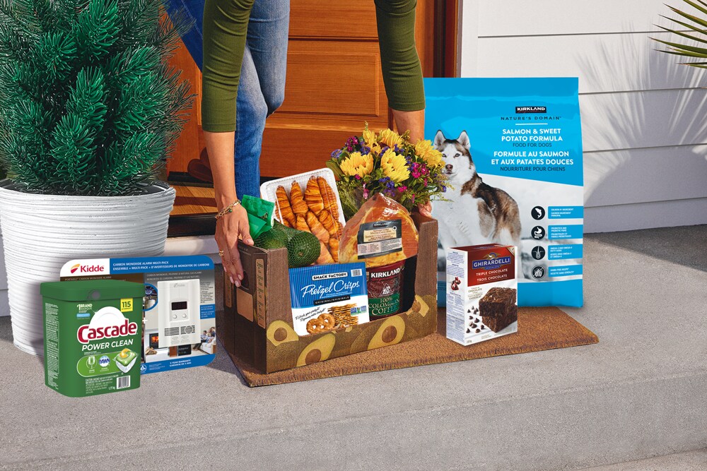 Person placing a grocery delivery box with assorted items on a doorstep.
