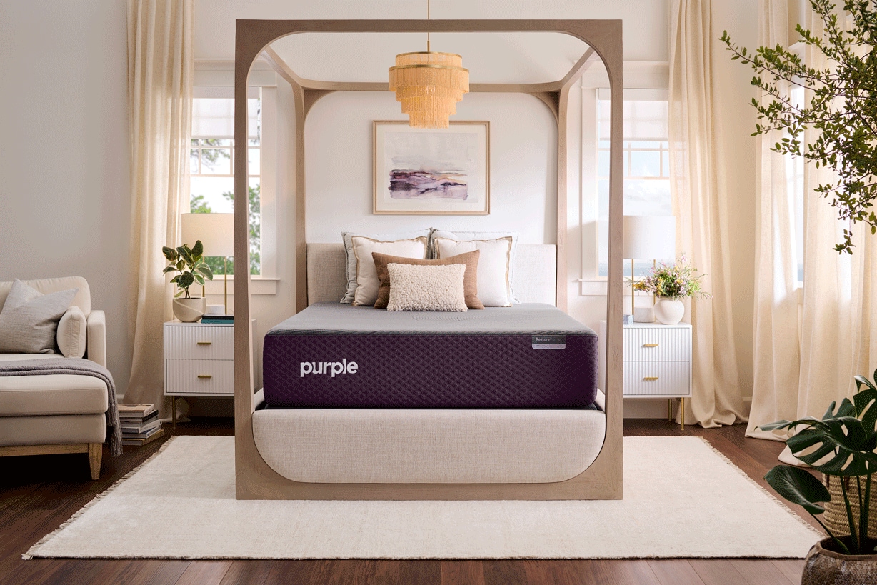Modern bedroom with a Purple brand mattress set in an elegant, well-lit room with white furnishings and green plants