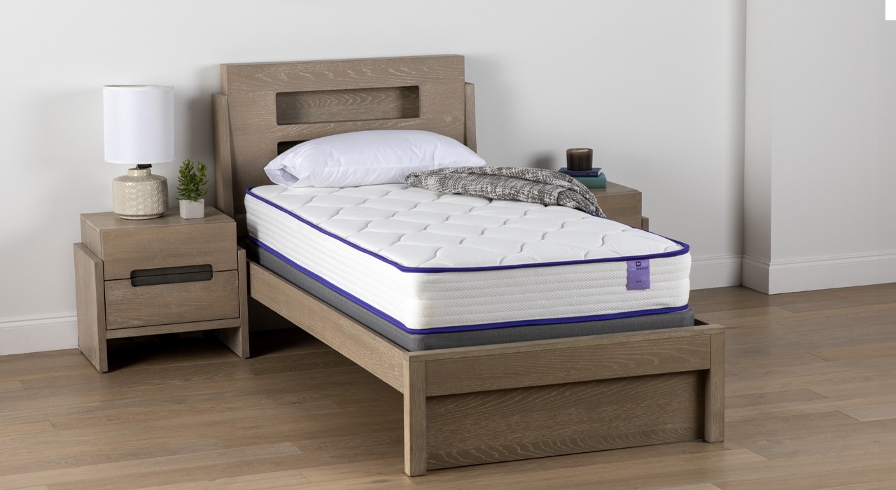 Minimalist bedroom with a single bed and matching nightstand in a neutral color scheme