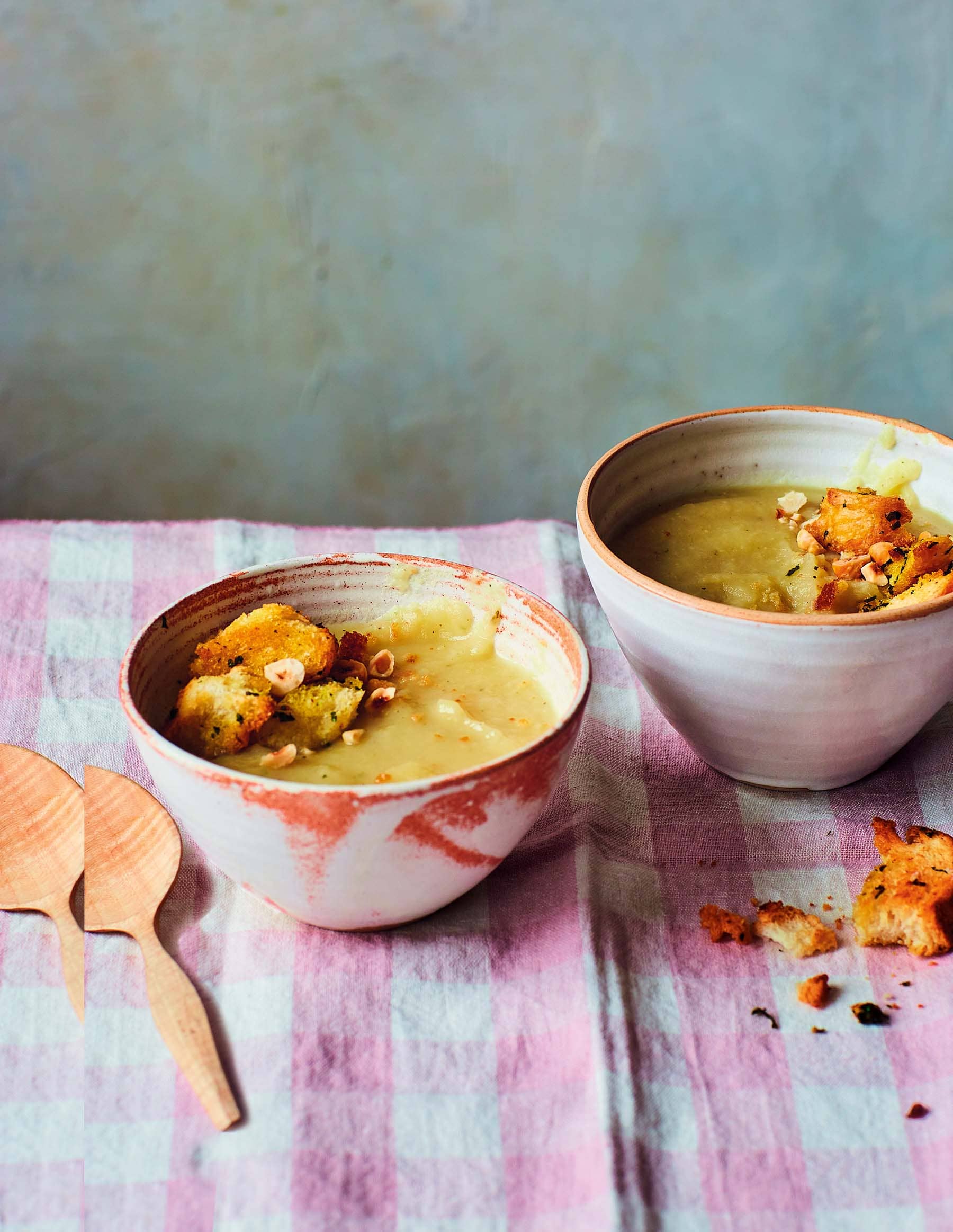 Deux bols de soupe crémeuse garnie de croutons, sur une nappe à motifs