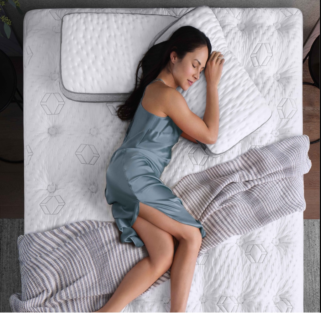 Woman in blue dress sleeping comfortably on a bed with striped blanket
