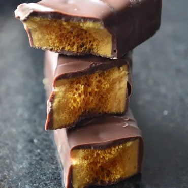Stack of chocolate-covered honeycomb candy bars with visible airy layers