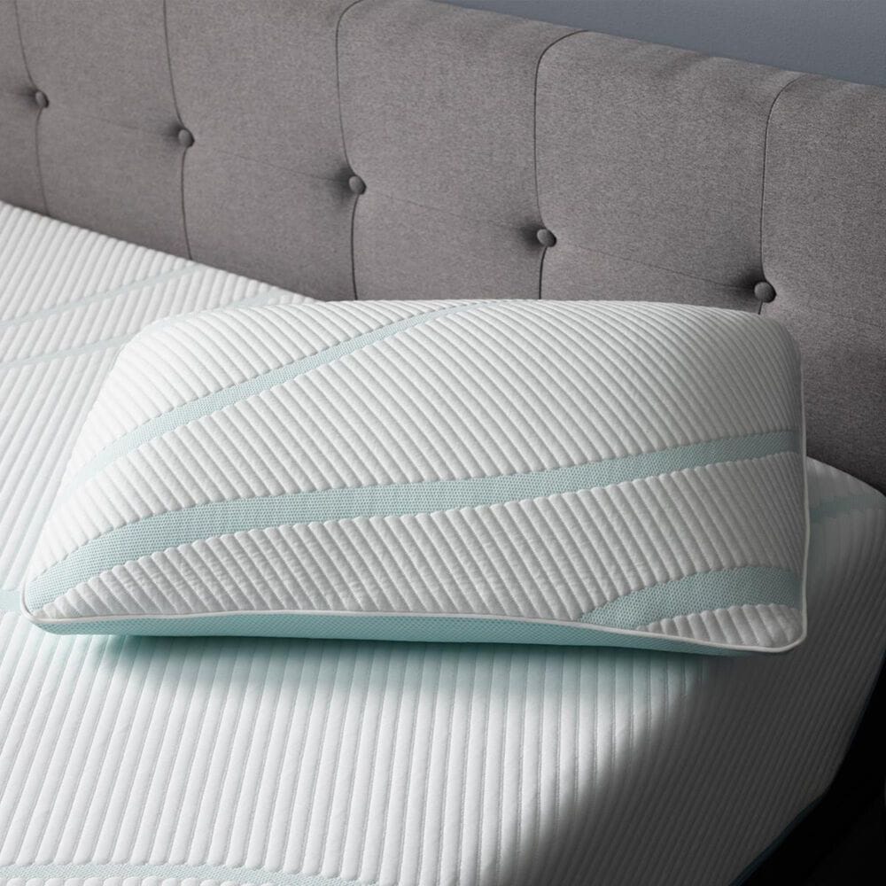 Memory foam pillow on a striped bedsheet against a gray tufted headboard