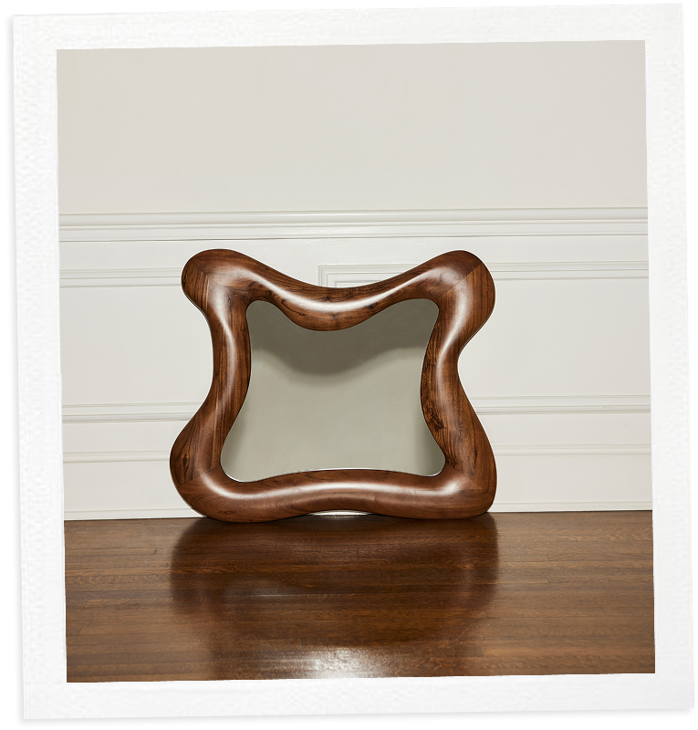 A wavy-edged wooden photo frame on a wooden surface against a white background