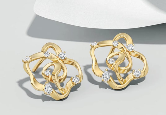 Gold earrings with intricate loops and diamond accents on a white surface