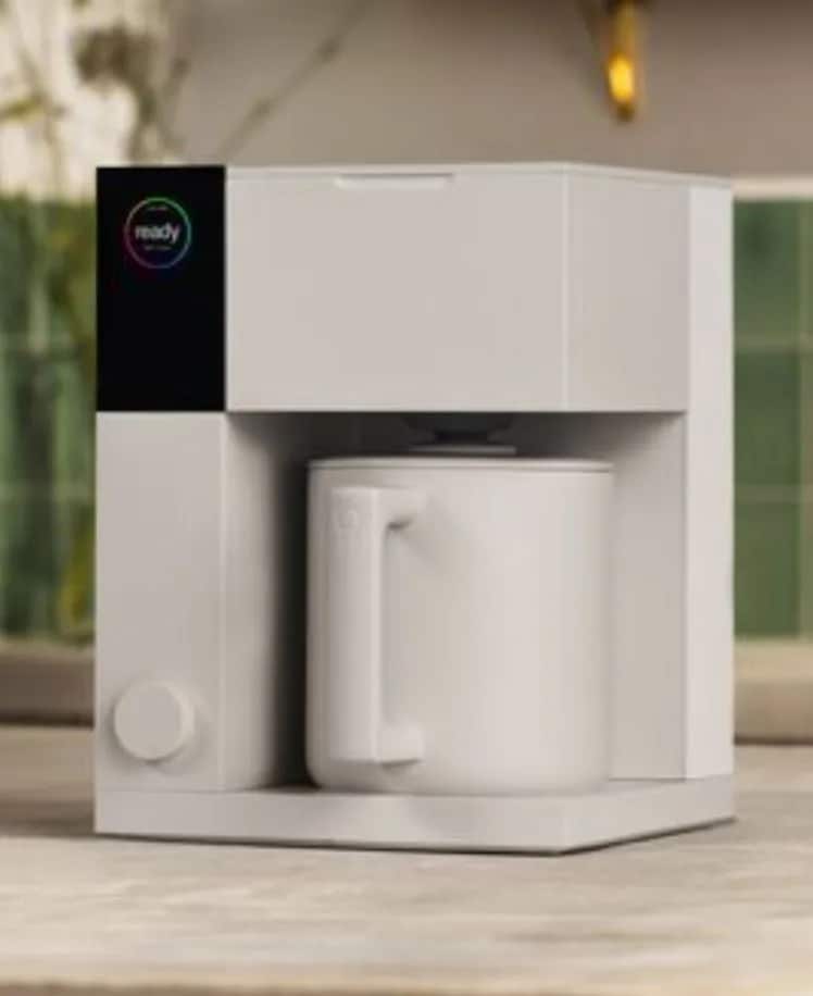 Modern white coffee maker with a mug on a kitchen counter