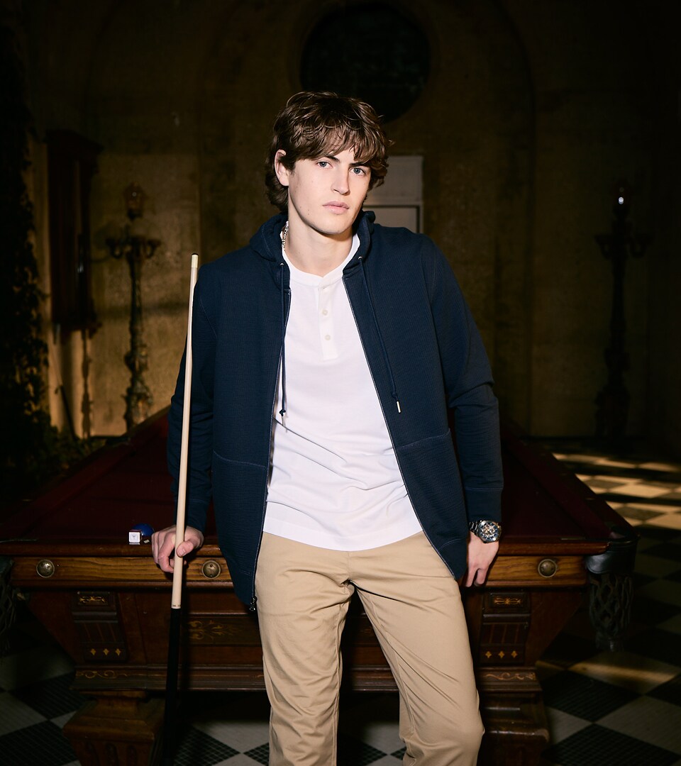 Young man in casual attire holding a pool cue in a dimly lit, vintage room