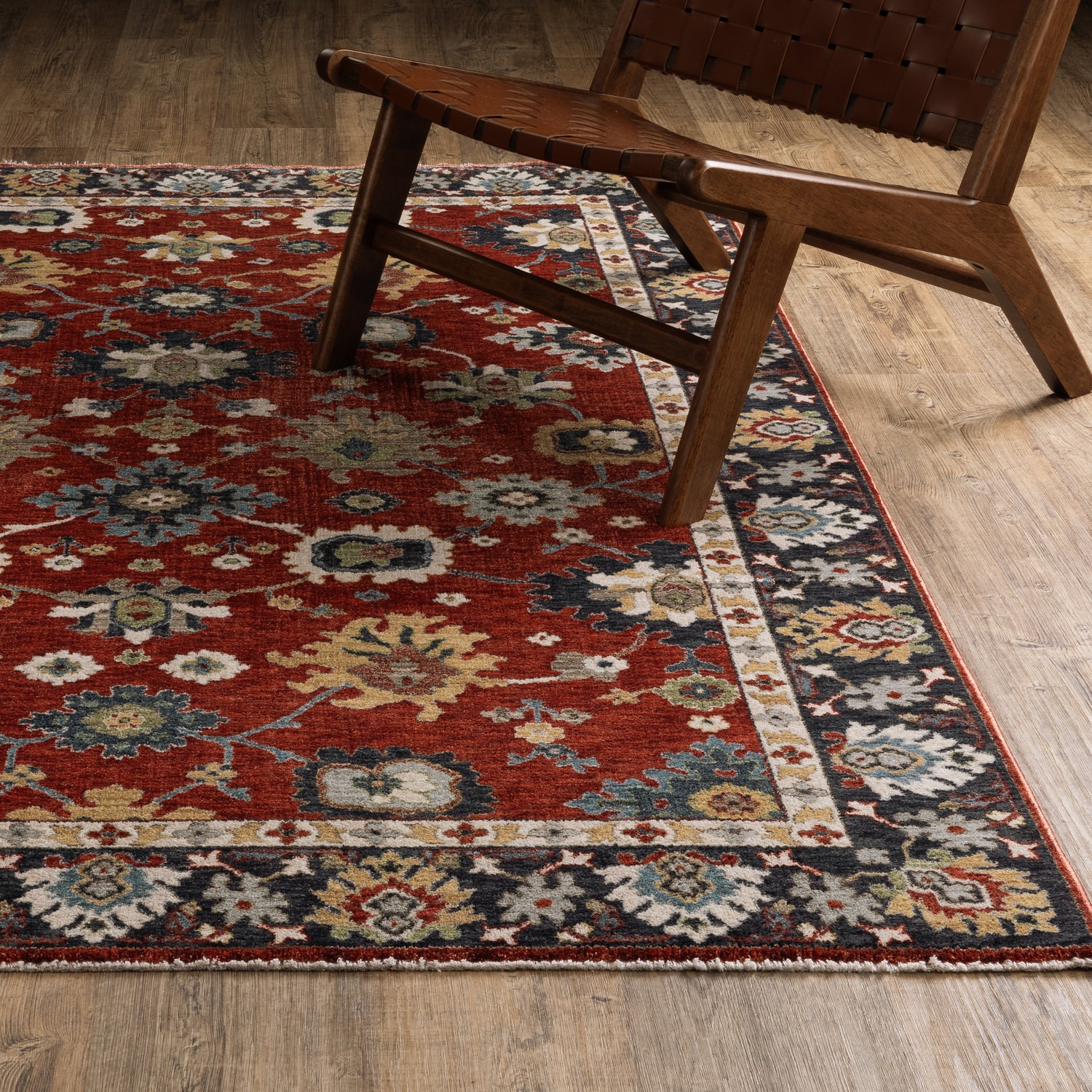 A red ornate rug under a wooden chair on a wooden floor