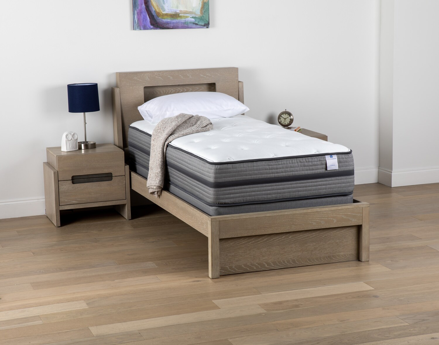 Modern bedroom with a single bed, side table, and lamp on a wooden floor