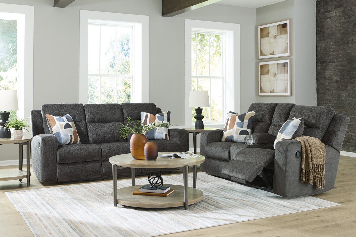 Modern living room with gray sofas, a coffee table, decorative pillows, and large windows