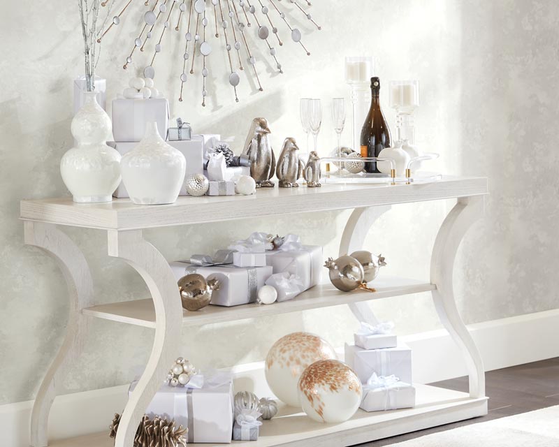 Elegant console table with holiday decorations and a bottle of champagne