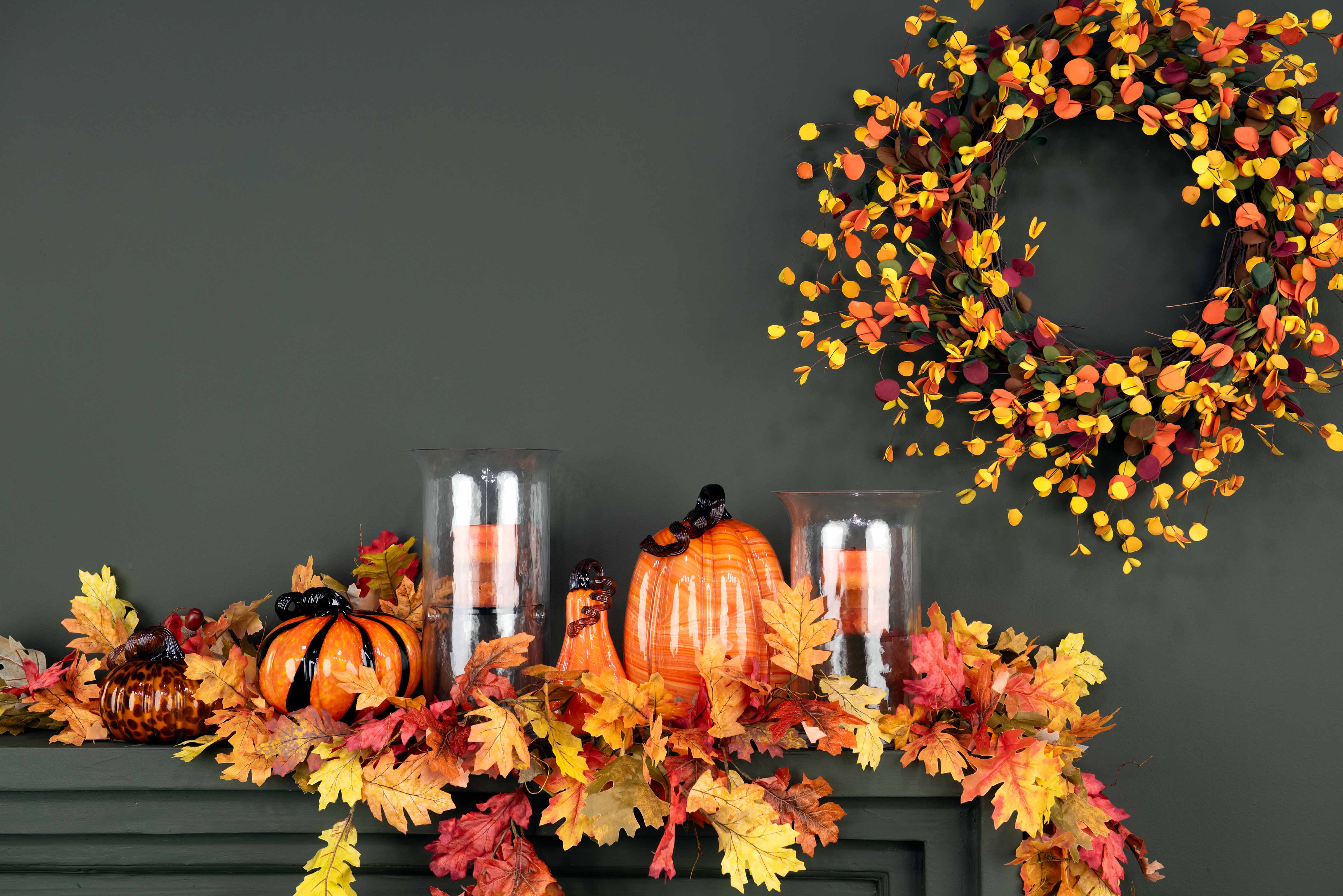 Autumn-themed decor with pumpkins and candles on a mantel, and a leafy wreath above