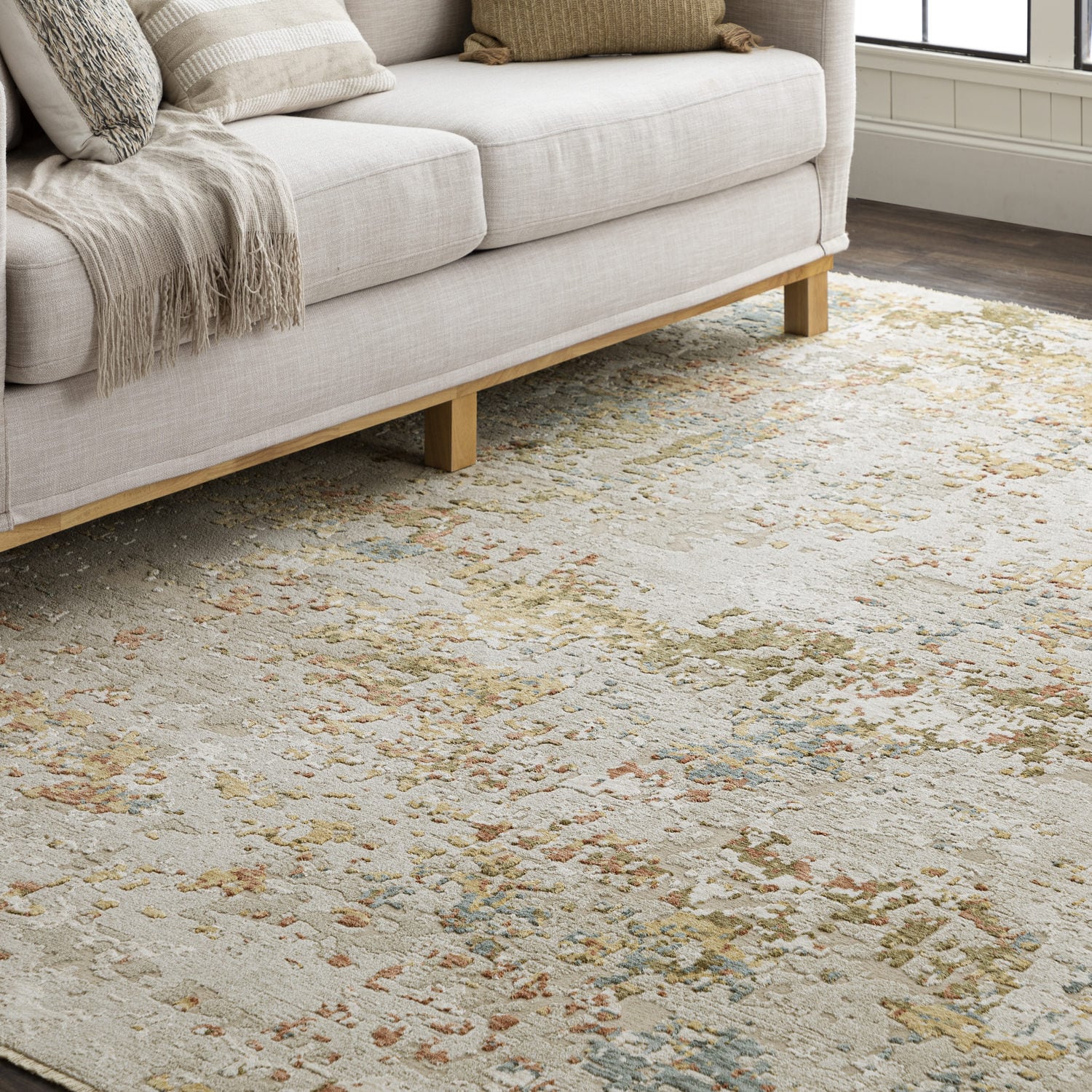 Beige sofa on a multicolored distressed rug in a cozy room setting