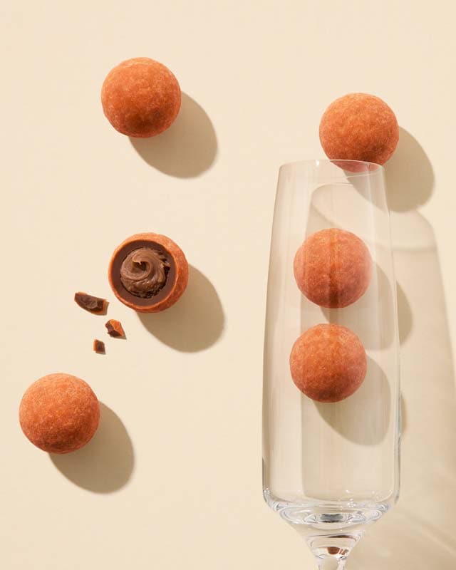 Champagne glass with lychees and an open lychee, on a beige background
