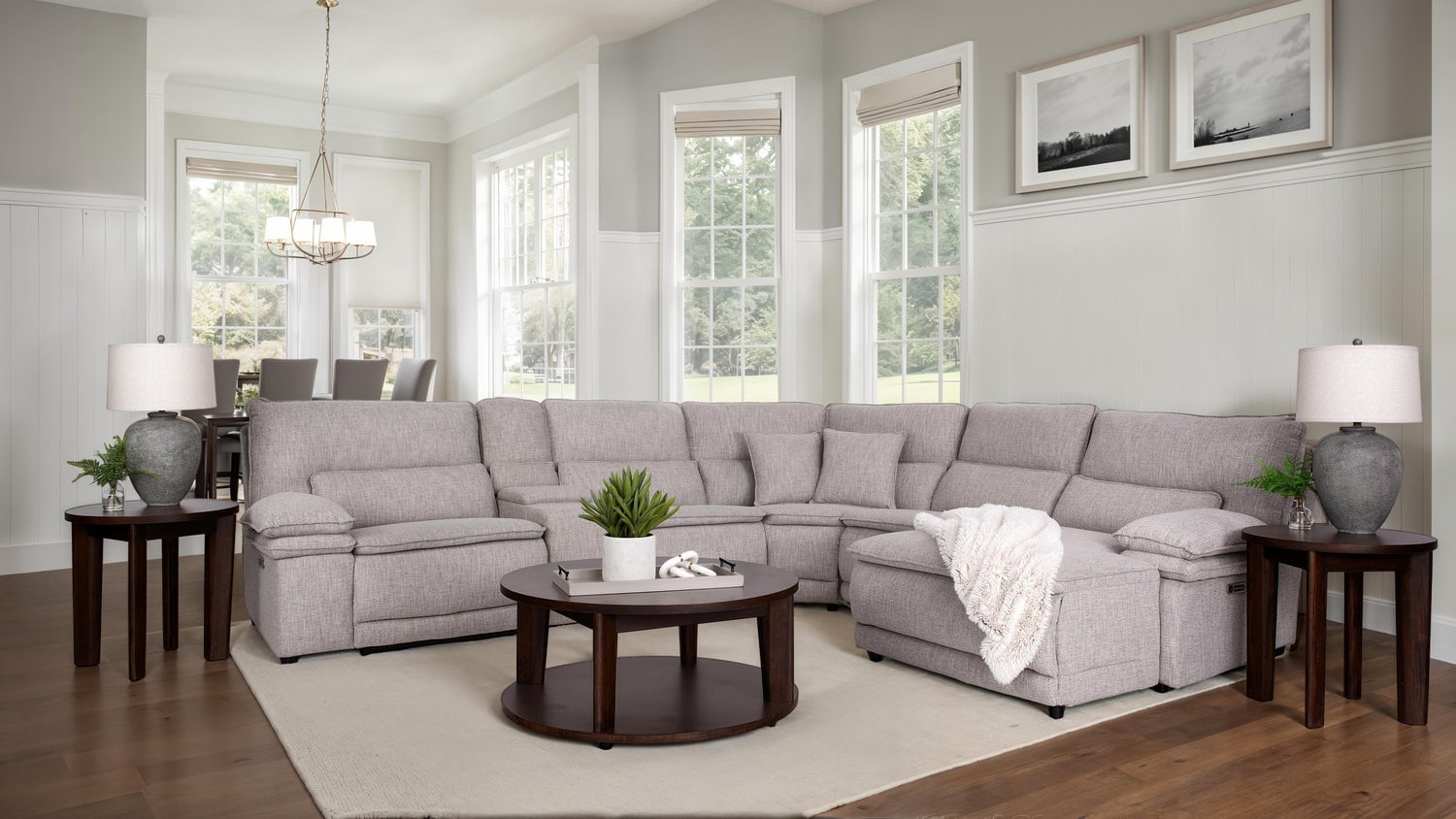 Modern living room with sectional gray sofa, coffee table, lamps, and framed art
