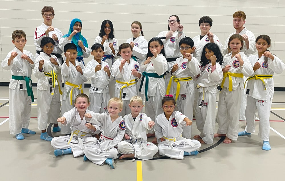 Groupe d'enfants en uniforme de karaté posant dans un gymnase