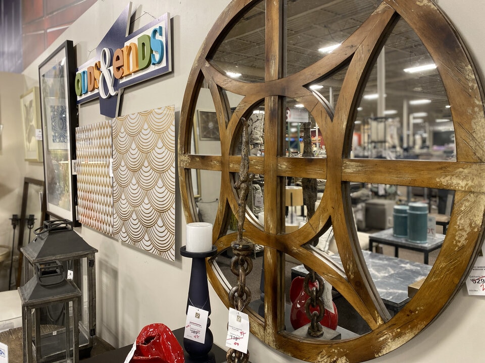 Large wooden decorative wheel in a store with various home decor items in the background