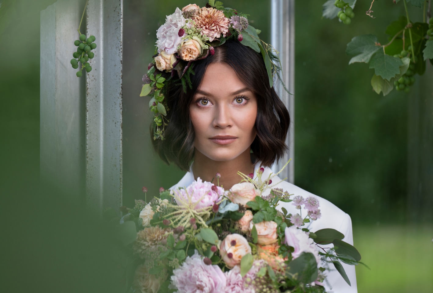 Woman with floral crown holding bouquet, looking through a window pane