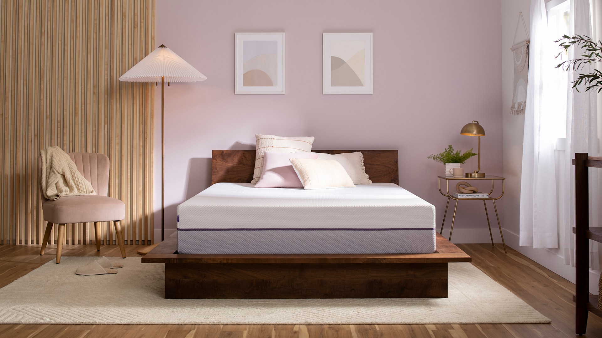 Modern bedroom with a large bed, wooden floor, soft pink walls, and minimalistic decor