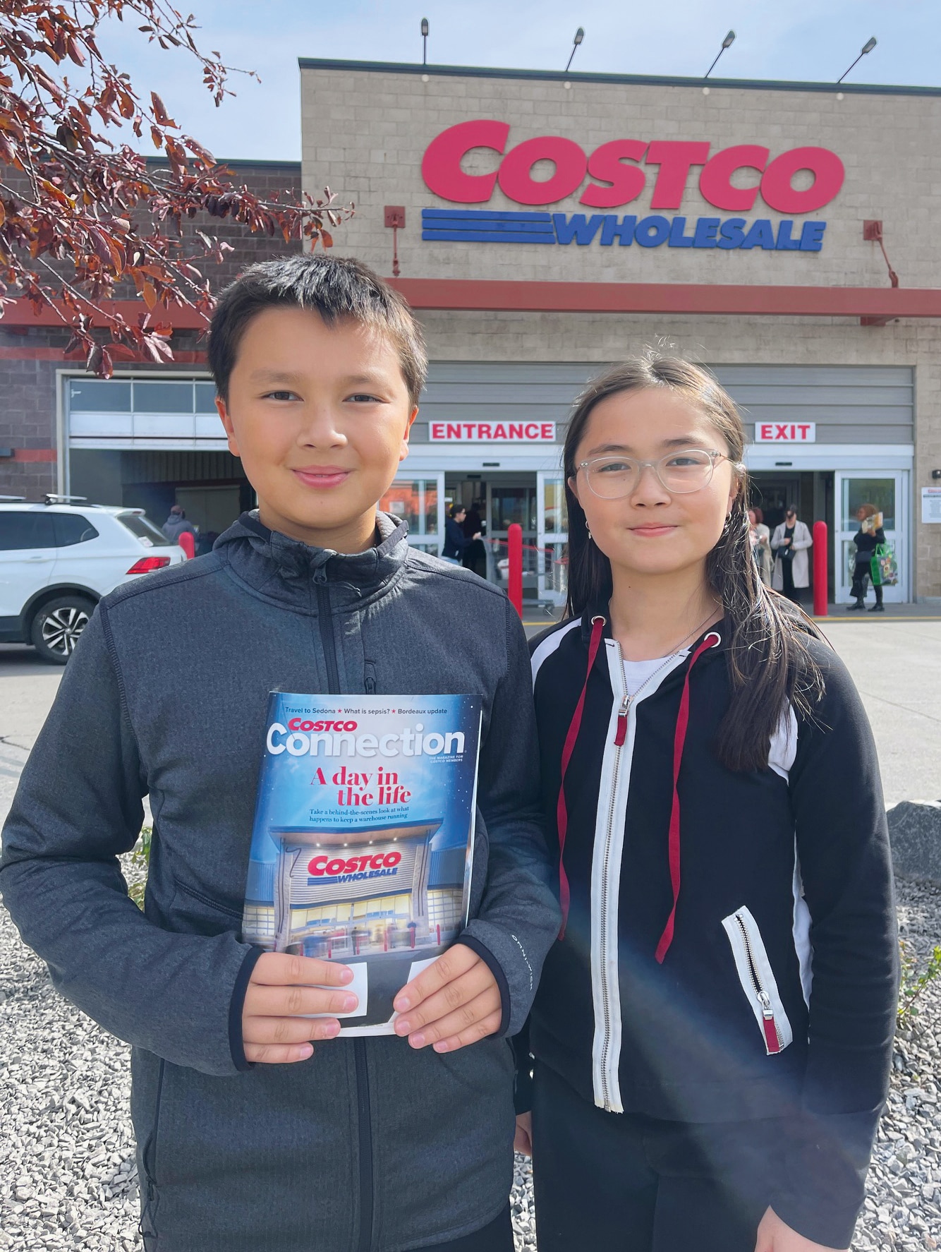 Jeune garçon et fille devant Costco, tenant le magazine "Connection"