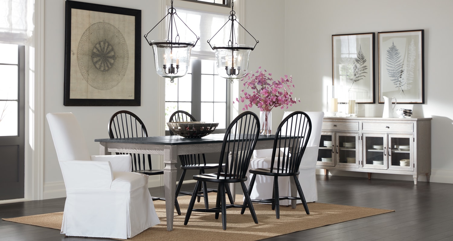 Elegant dining room with a modern table, mix-matched chairs, pendant lights, and minimalist artwork