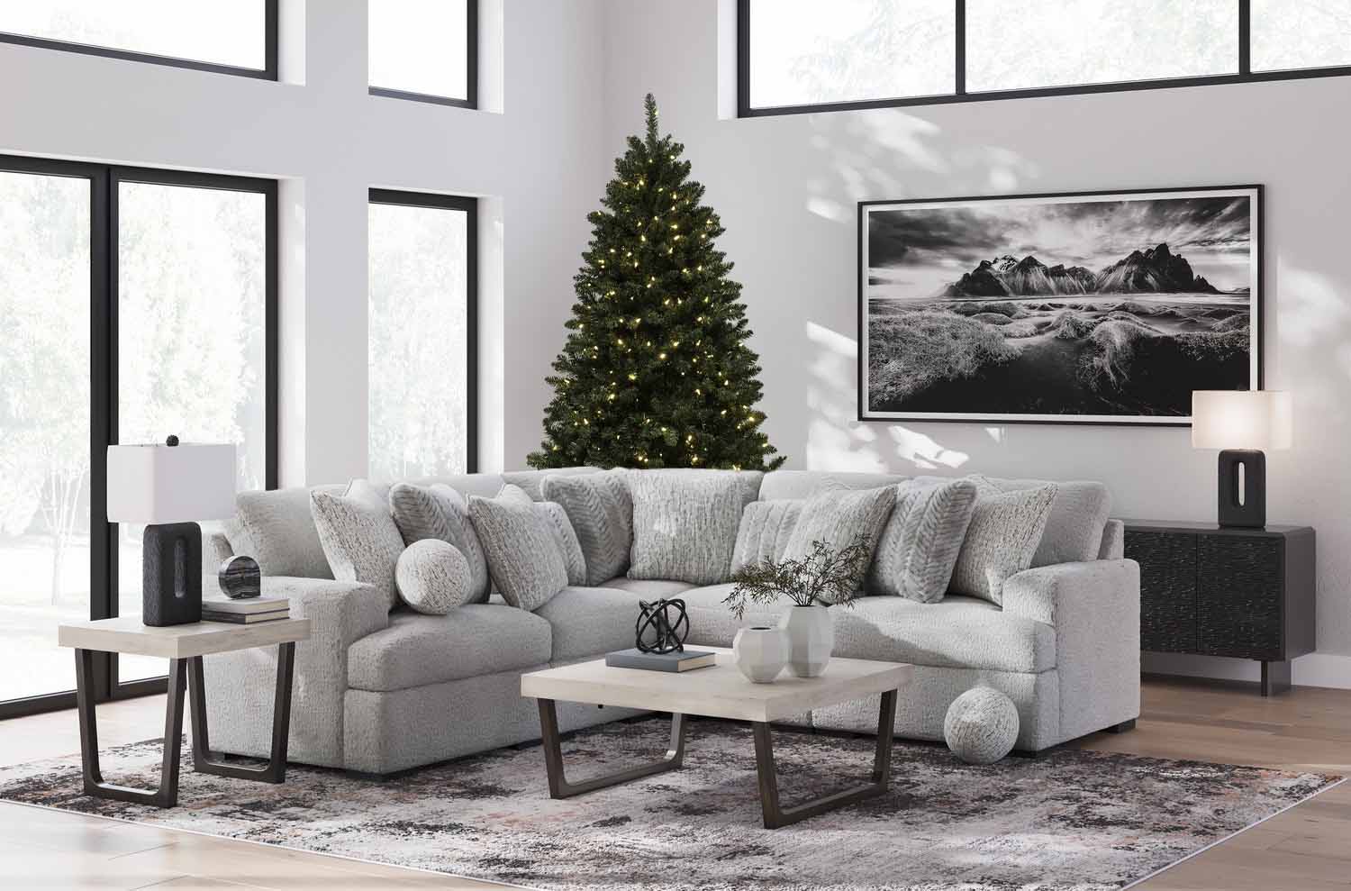 Modern living room with a Christmas tree, large couch, and monochrome artwork