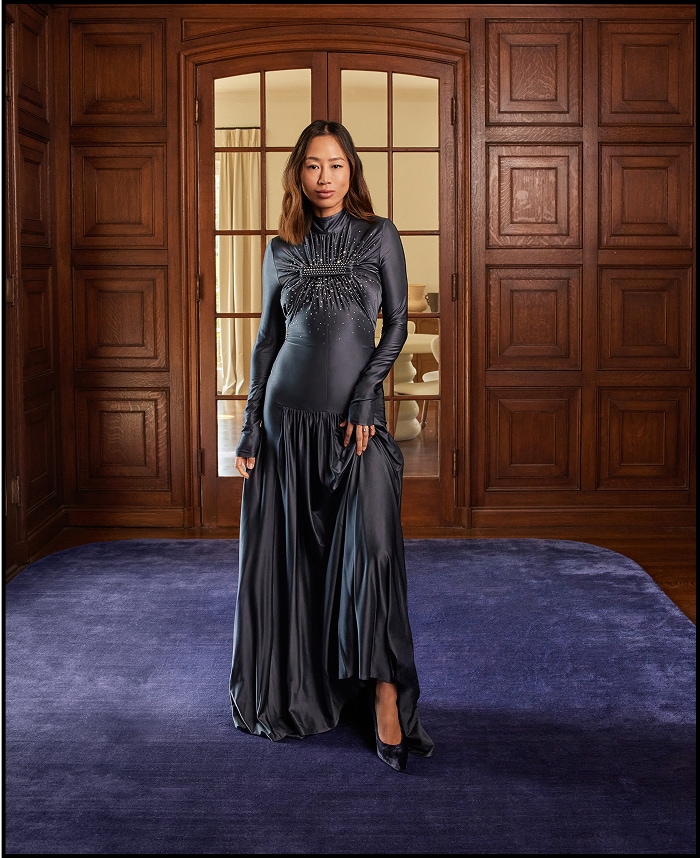 Pregnant woman in elegant black dress standing in room with wooden doors
