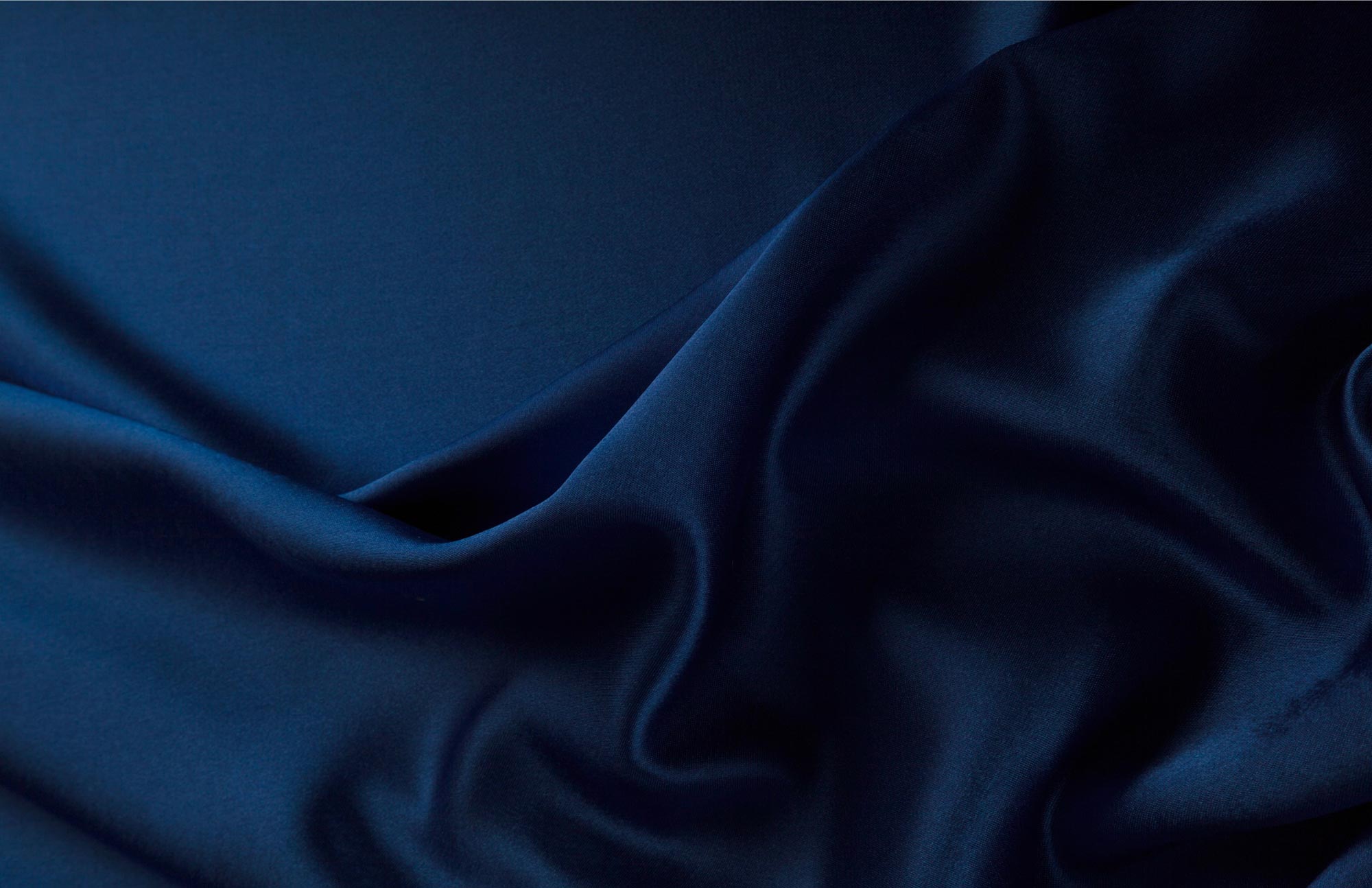 Close-up of elegant dark blue satin fabric with soft folds