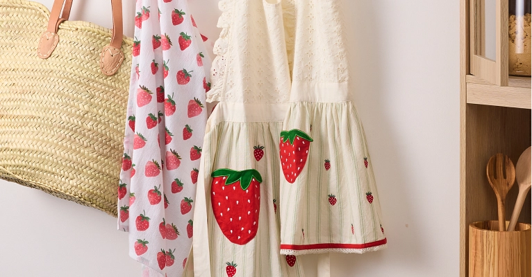 Sur La Table Embroidered Strawberry Aprons and strawberry motif flour sack towel hanging on hooks