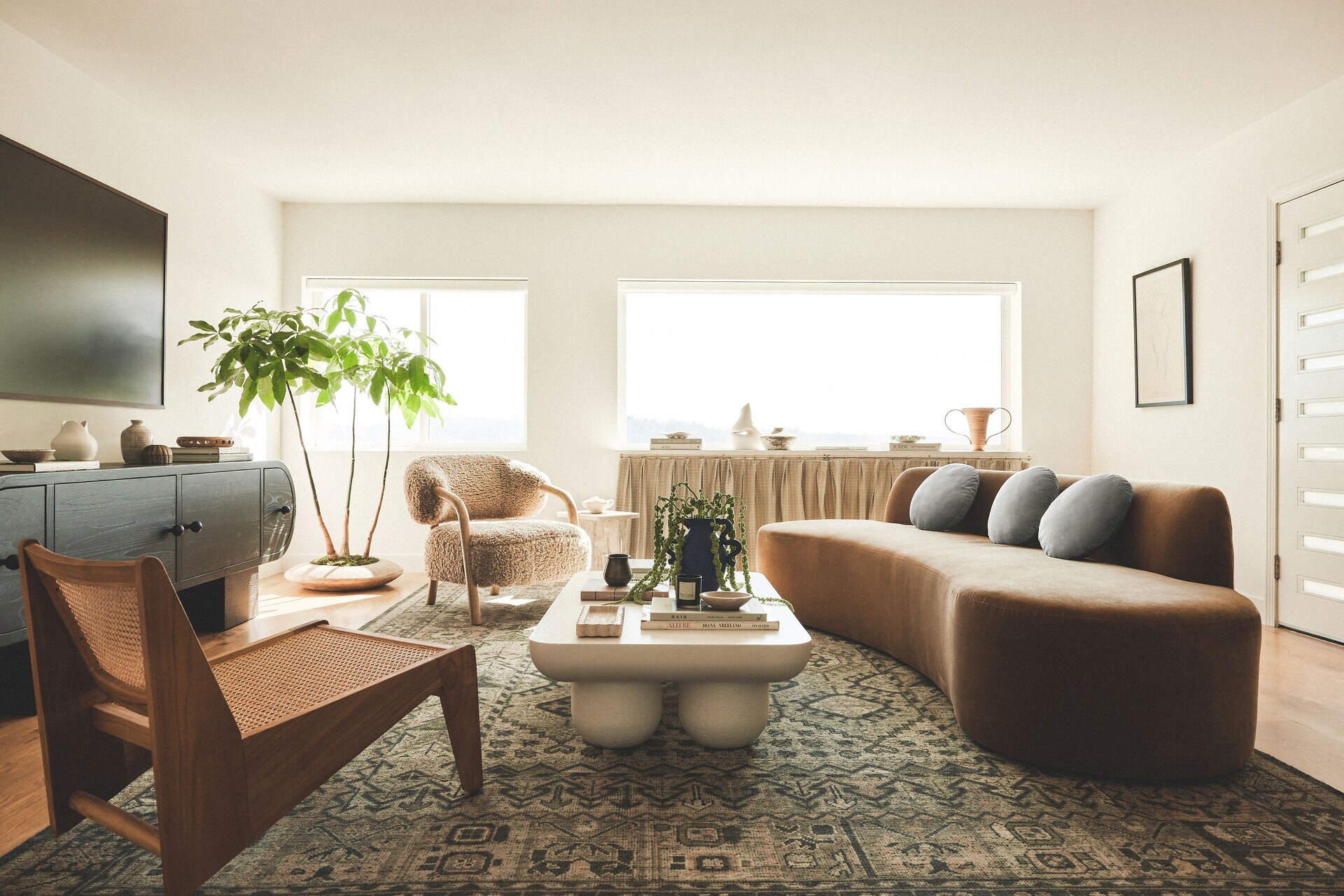 Modern living room with sofa, chairs, coffee table, and a large potted plant