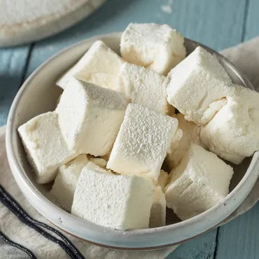 A bowl of cubed white tofu on a wooden table