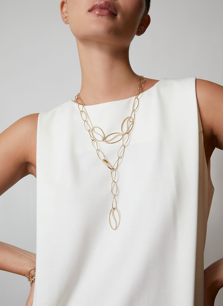 Woman in white top wearing a large gold chain necklace