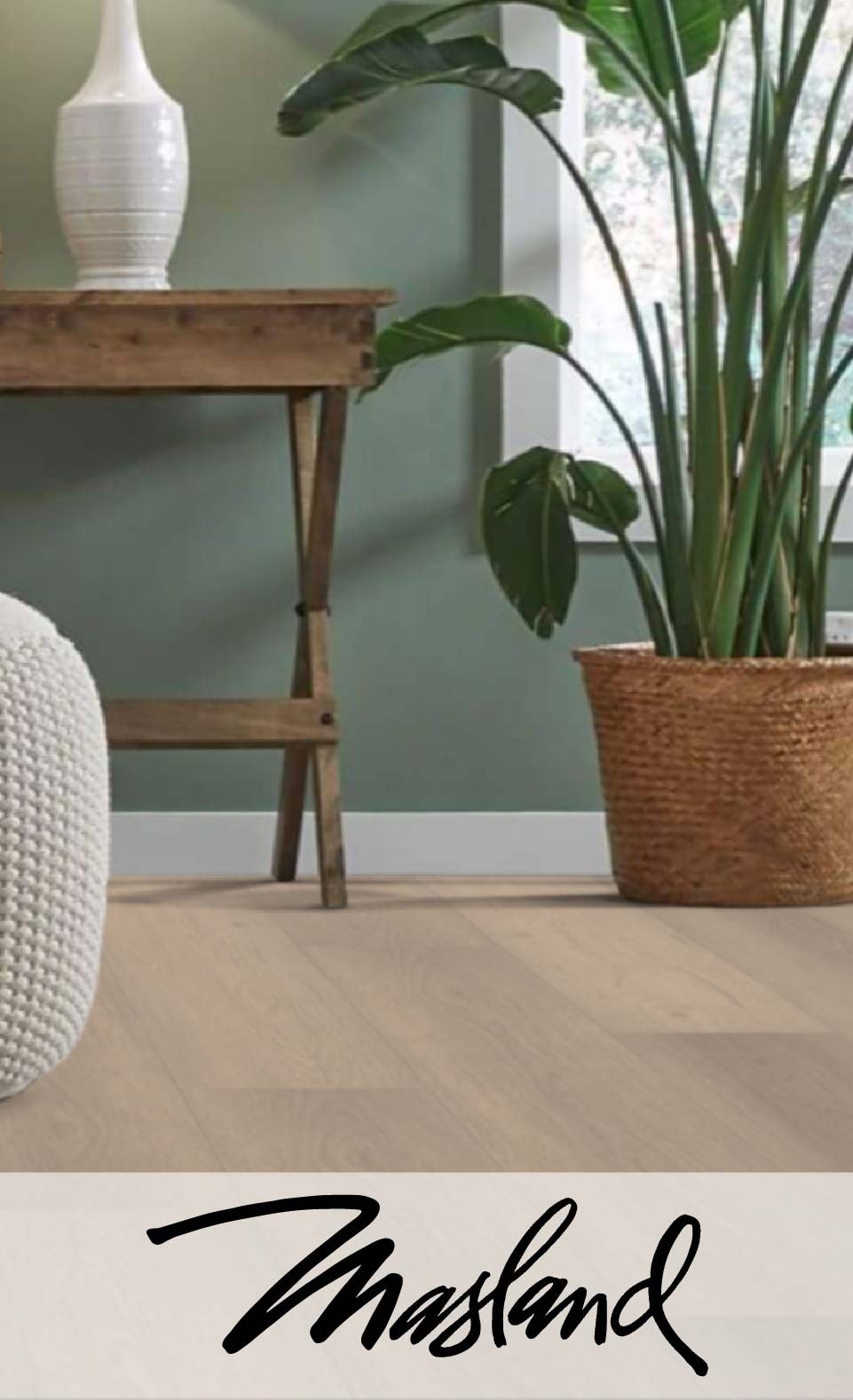 Elegant interior with wooden table, wicker basket plant, white vase, and green walls with "Masland" script at the bottom