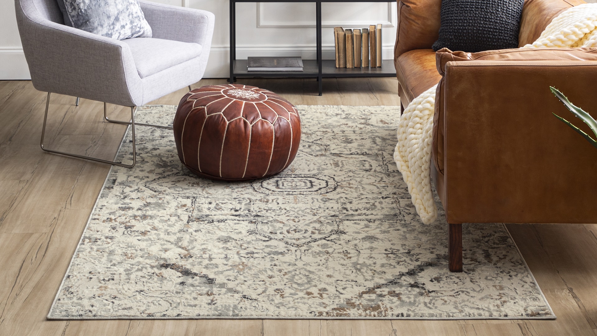 Stylish living room with a patterned rug, leather chair, white armchair, and a red pouf