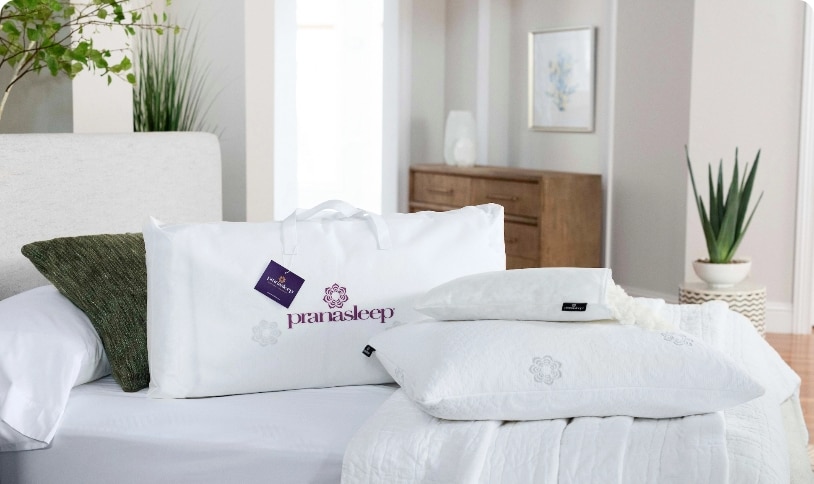 Bright bedroom with white bedding and decorative pillows, including one with a logo