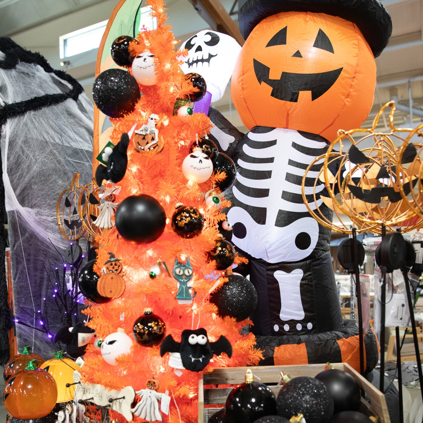 Halloween display with an orange tree decorated with black ornaments, a pumpkin balloon, and a skeleton