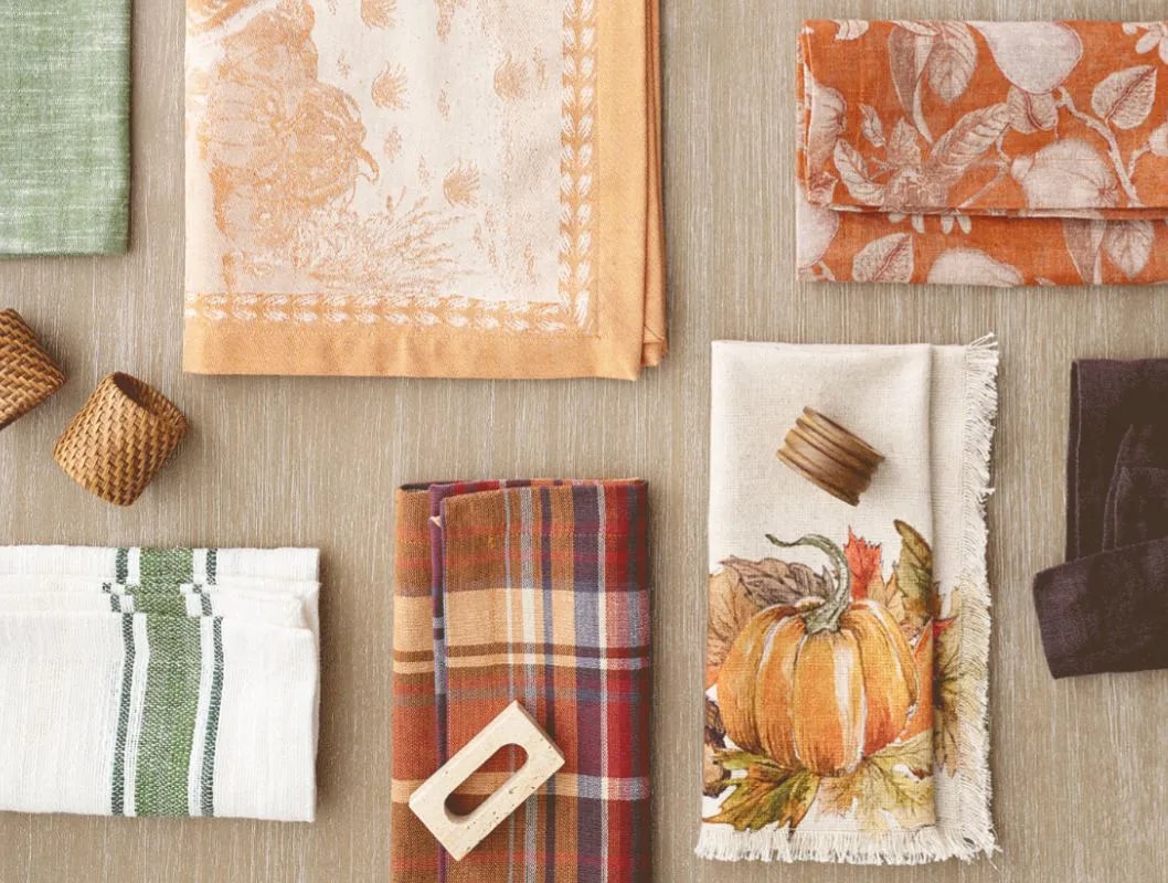 Assorted patterned fabrics and napkins with decorative items on a wooden surface