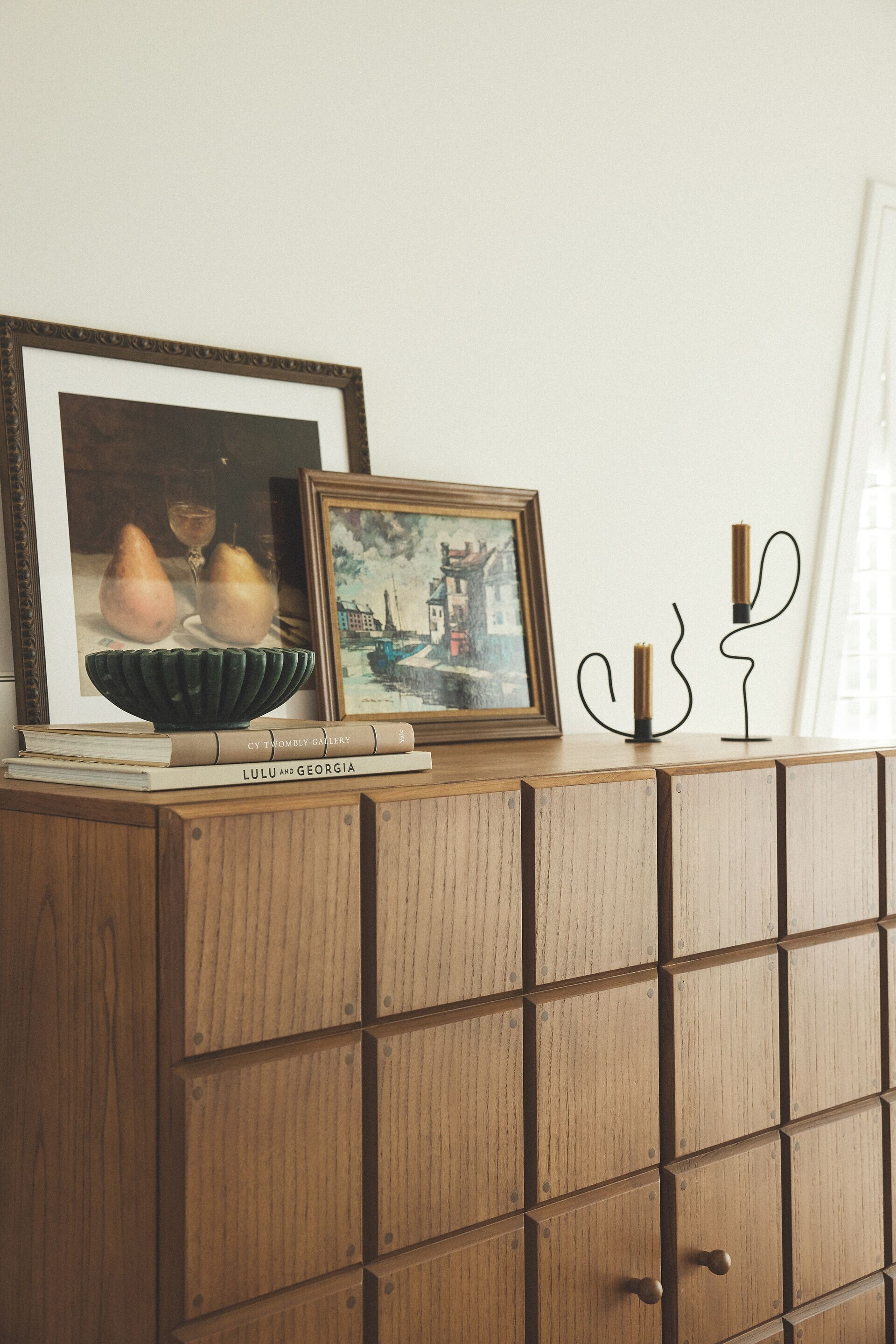 Wooden cabinet with framed art and candle holders in a tidy room
