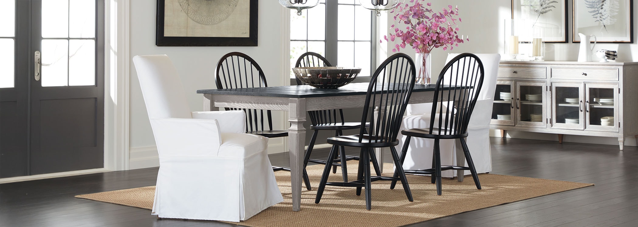 Modern dining room with a gray table, black chairs, white armchair, and a side cabinet