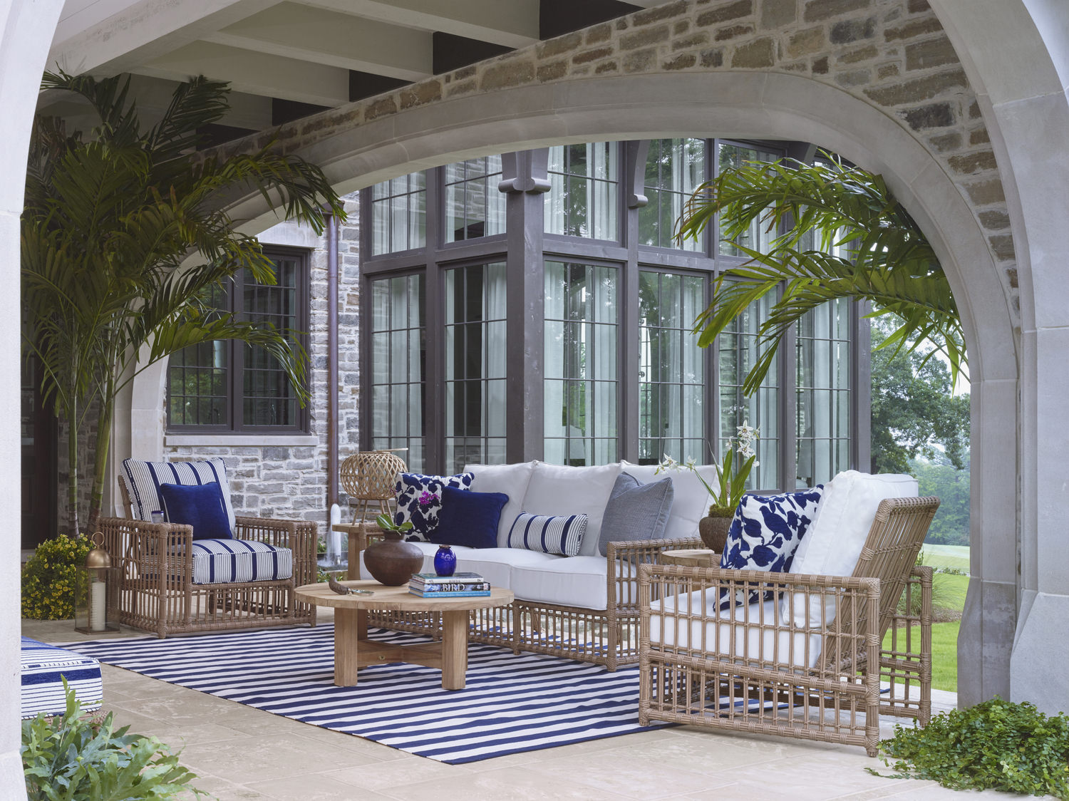 Elegant outdoor patio with sofa, chairs, and table under a white arched pavilion