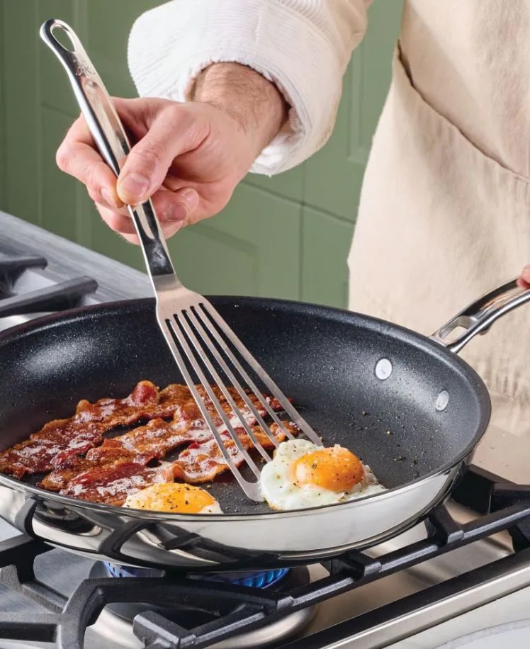 Person cooking bacon and eggs in a frying pan on a stove