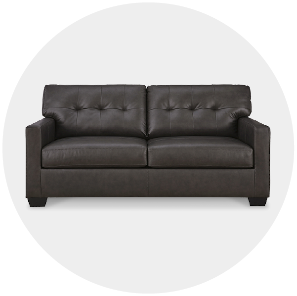 A dark gray tufted two-seater sofa on a white background